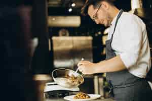 Free photo man chef cooking asian chicken at a cafe kitchen