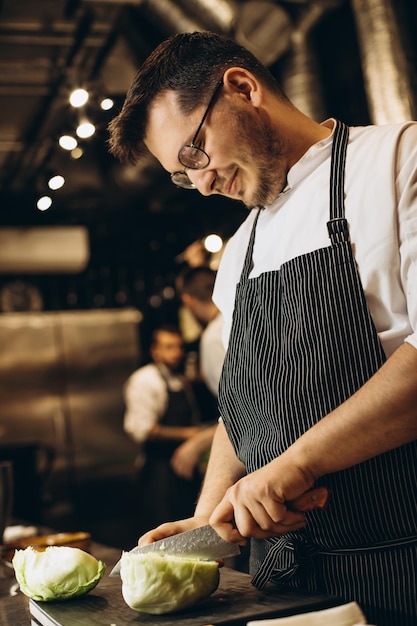 Man chef cutting cabbage at the kitchen restaurant