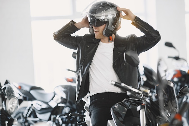 Free photo man choosed motorcycles in moto shop. guy in a black jacket. man in a helmet.