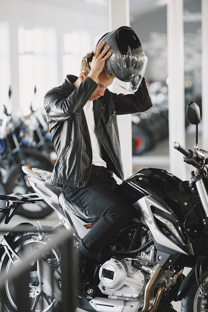 Free photo man choosed motorcycles in moto shop. guy in a black jacket. man in a helmet.