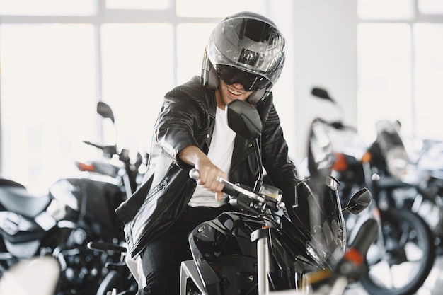 Free photo man choosed motorcycles in moto shop. guy in a black jacket. man in a helmet.