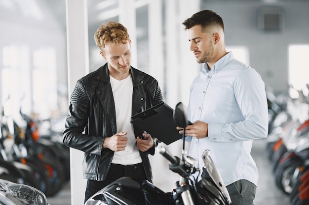 Free photo man choosed motorcycles in moto shop. guy in a black jacket. manager with client.