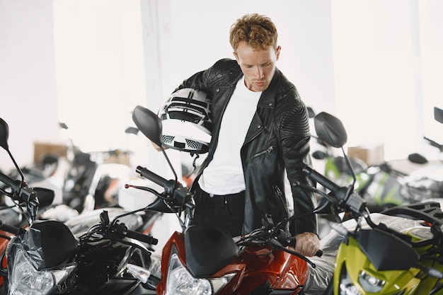 Man choosed motorcycles in moto shop. Guy in a black jacket.