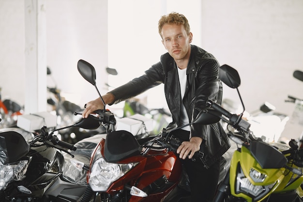 Man choosed motorcycles in moto shop. Guy in a black jacket.