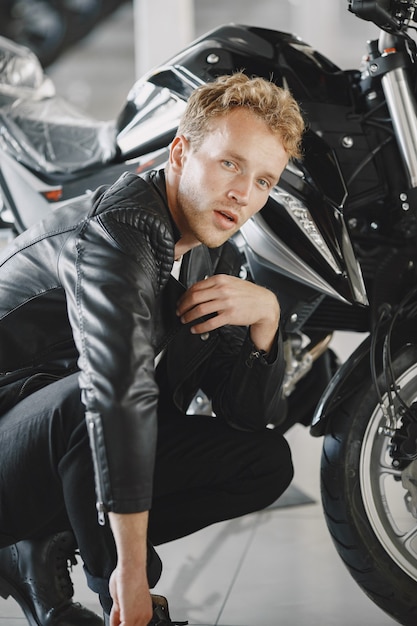 Free photo man choosed motorcycles in moto shop. guy in a black jacket.