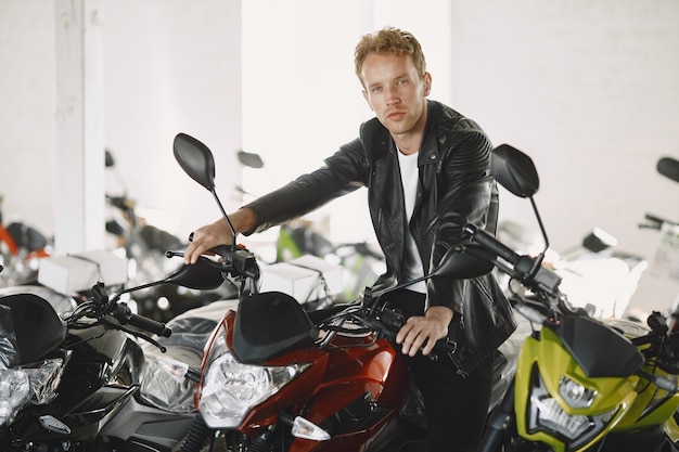 Free photo man choosed motorcycles in moto shop. guy in a black jacket.