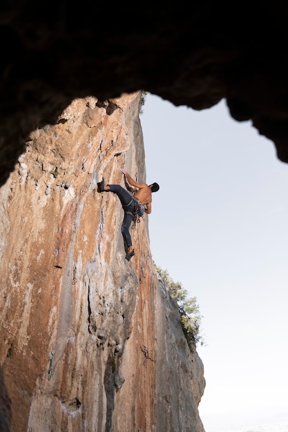 Free photo man climbing on a mountain with safety equipment