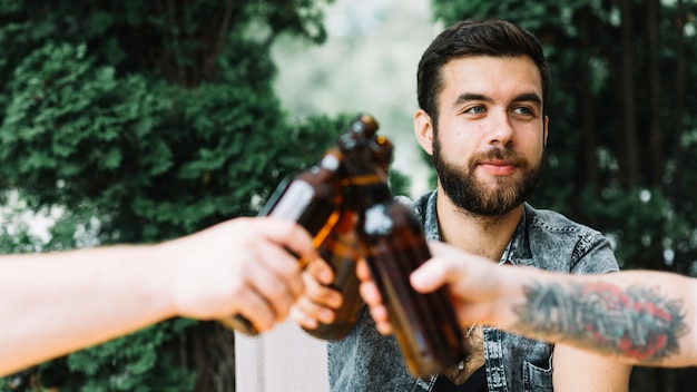 Man clinking beer bottles with his friends