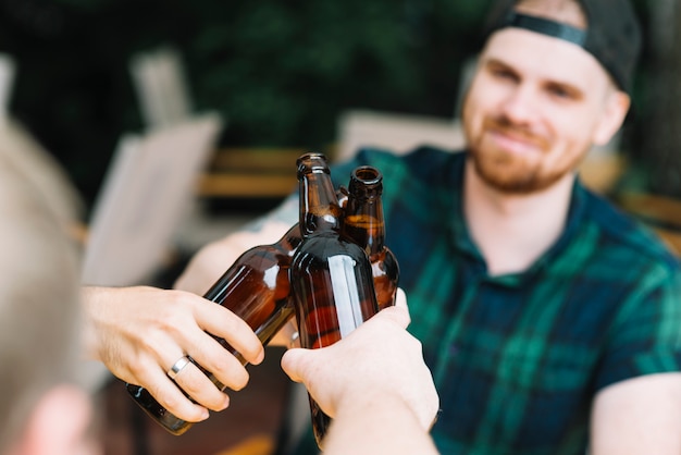 Free Photo man clinking the glass bottles of beer with friends