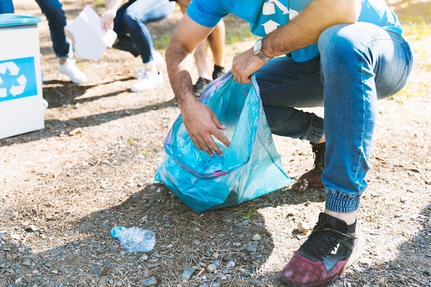 Free photo man collecting garbage in plastic bag