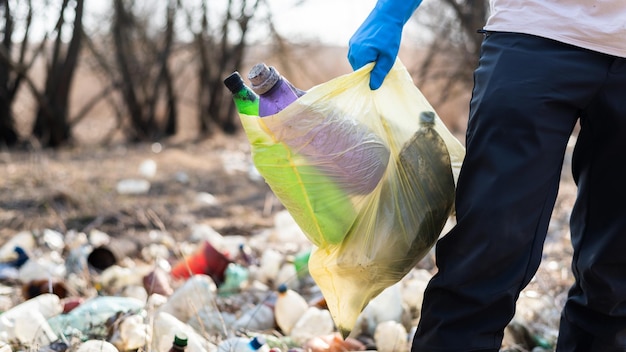 Man collecting scattered plastic bottles from the ground