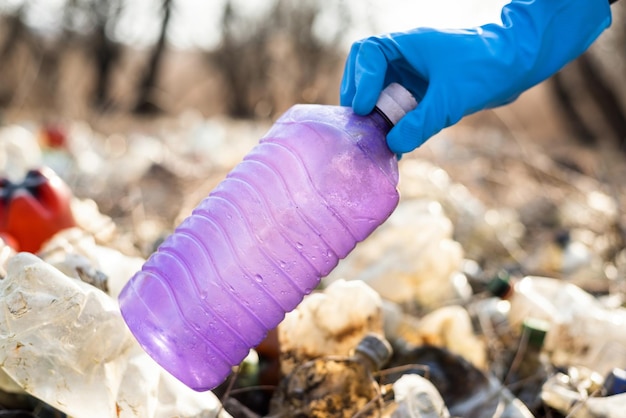 Free photo man collecting scattered plastic bottles from the ground