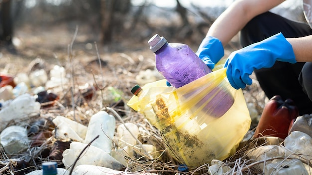 Free photo man collecting scattered plastic bottles from the ground