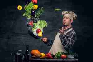 Free photo man cook holds a pan with vegetables flying in the  air.