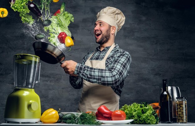 Man cook holds a pan with vegetables flying in the  air.