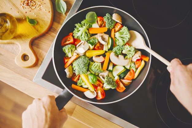 Free photo man cooking fresh vegetables on pan