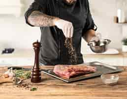 Free photo man cooking meat steak on kitchen