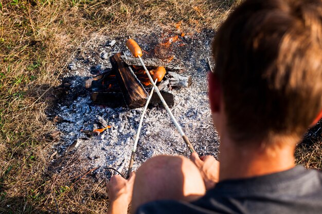 Man cooking sausages over the shoulder shot