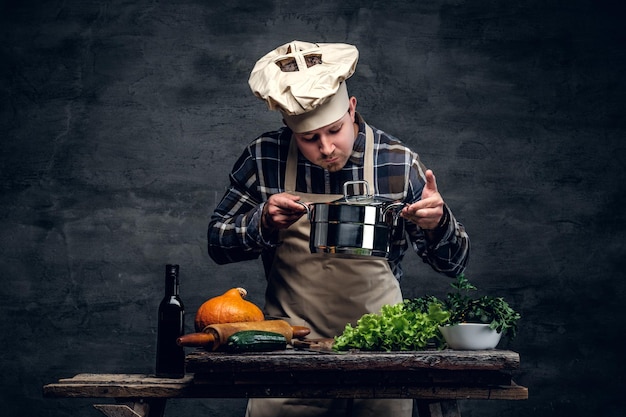 Free Photo a man cooking a soup and tasting it on a dark background.