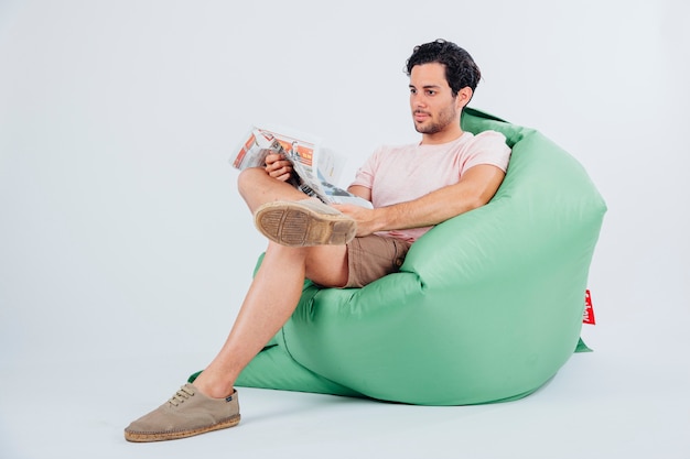 Free photo man on couch reading newspaper