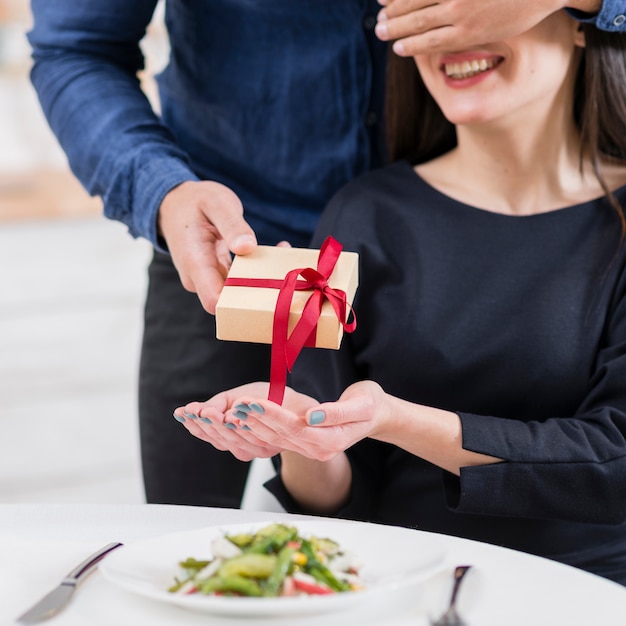 Free photo man covering his girlfriend's eyes before giving her a gift close-up