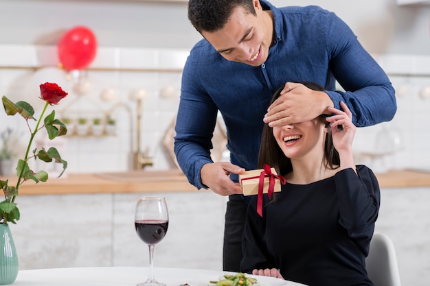 Man covering his girlfriend's eyes before giving her a gift