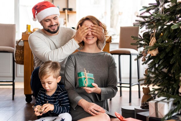 Man covering his wife's eyes for a christmas surprise