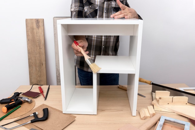 Free photo man creating a cabinet from wood front view