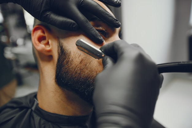 The man cuts his beard in the barbershop