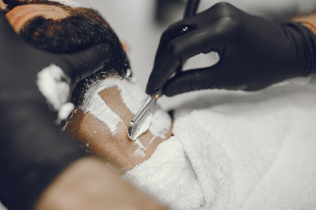 The man cuts his beard in the barbershop