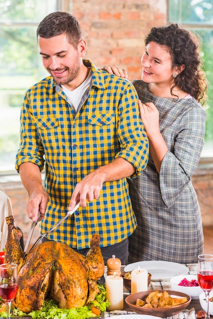 Free photo man cutting baked chicken at table near woman