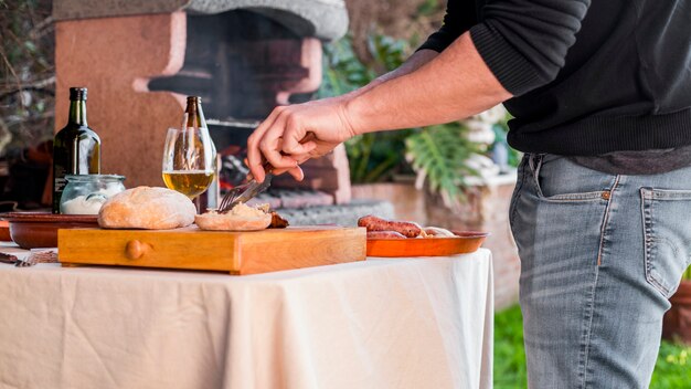 Man cutting bread and grilled chicken with fork and knife at outdoors