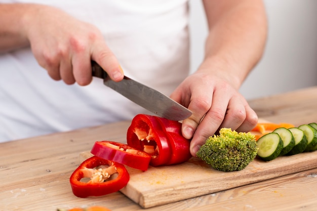 Man cutting vegetables on a wooden tray