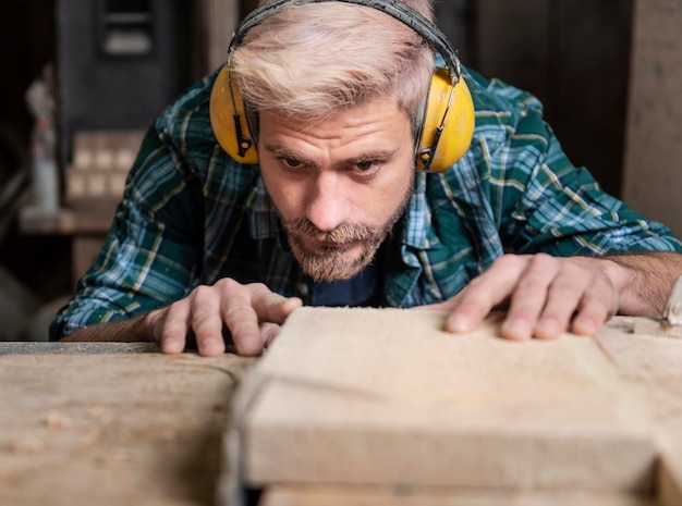 Free Photo man cutting wood planks