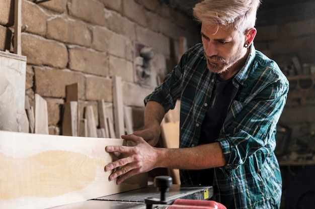 Free photo man cutting wood planks