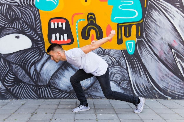 Free Photo man dancing in front of painted wall