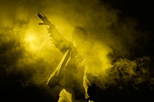 Free photo man dancing in smoke with illuminating light