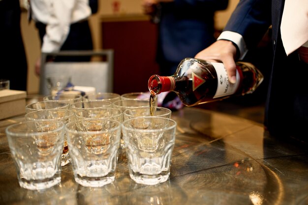 Free photo man in dark blue suit pours whisky in the glasses