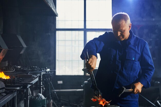 Man in dark blue uniform working with hammer and plier