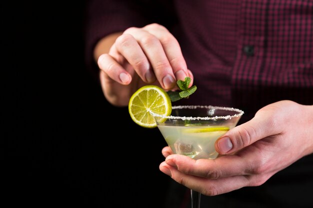 Man decorating cocktail glass with mint