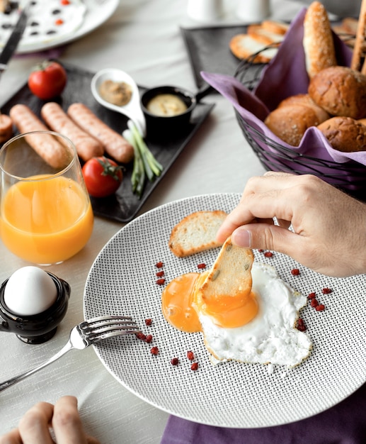 Free photo man dipping roast into egg yellow for breakfast