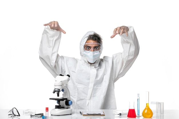 man doctor in protective suit and with mask quietly sitting on light white