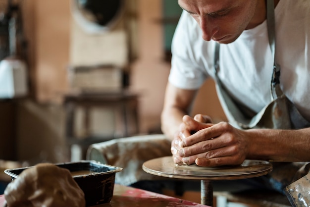 Free photo man doing pottery in studio side view