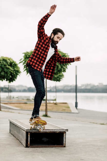 Free photo man doing skateboard tricks on a bench