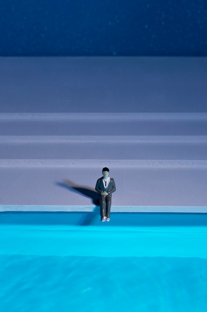 Free Photo man doll sitting next to swimming pool