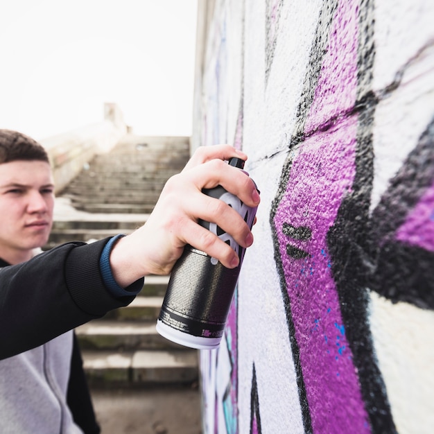 Free photo man drawing graffiti at street wall