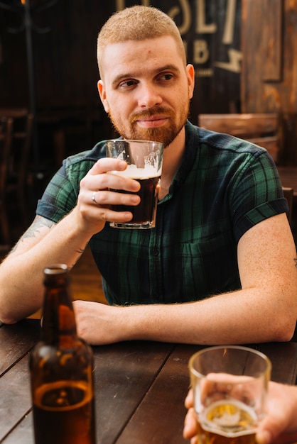 Free photo man drinking beer in bar