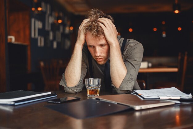 Man drinks whiskey. Businessman reads documents. Director in a shirt and suspenders.