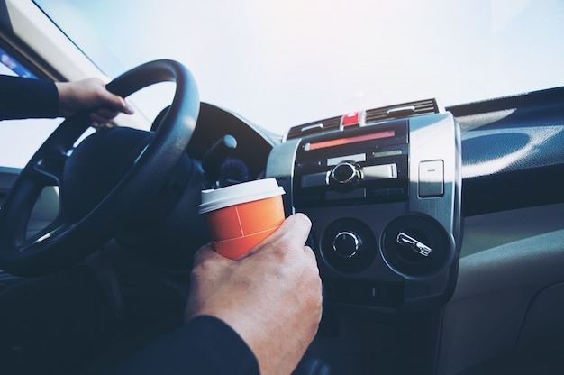 Man drive car while holding a cup of hot coffee - car driving sleepy or asleep concept