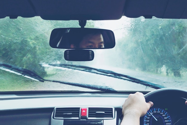 Free photo man driving car in heavy rainfall